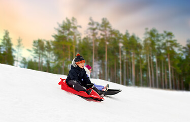 Image showing happy kids sliding on sleds down hill in winter