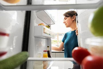 Image showing woman at open fridge at home kitchen