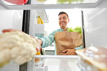 Image showing man putting new purchased food to home fridge