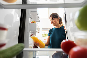 Image showing happy woman taking juice from fridge at home