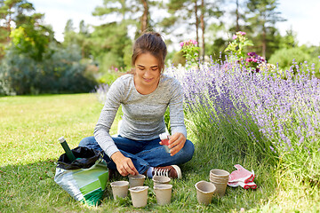 Image showing woman planting seeds to pots at summer garden