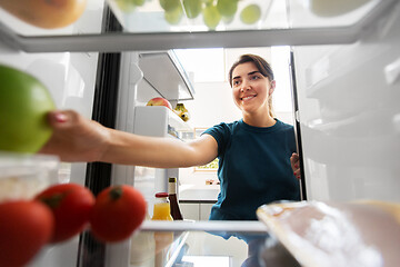 Image showing happy woman taking food from fridge at home