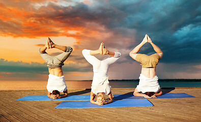 Image showing people making yoga headstand on mat outdoors