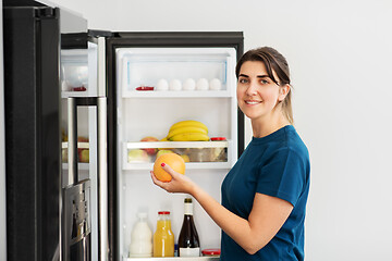 Image showing happy woman taking food from fridge at home