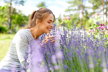 Image showing young woman smelling lavender flowers in garden