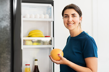 Image showing happy woman taking food from fridge at home