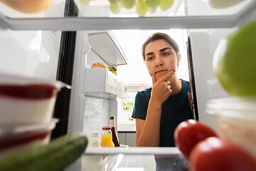 Image showing thoughtful woman at open fridge at home kitchen