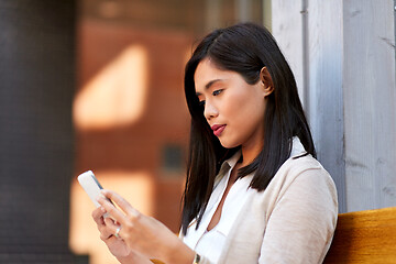 Image showing asian woman using smartphone sitting on bench