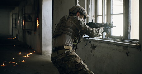 Image showing soldier in action near window changing magazine and take cover