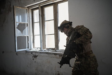 Image showing soldier in action near window changing magazine and take cover