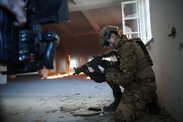 Image showing soldier in action near window changing magazine and take cover