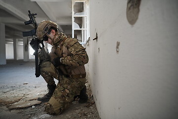 Image showing soldier in action near window changing magazine and take cover