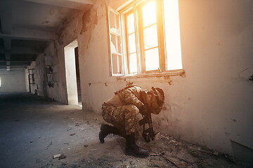 Image showing soldier in action near window changing magazine and take cover