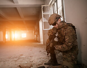 Image showing soldier in action near window changing magazine and take cover