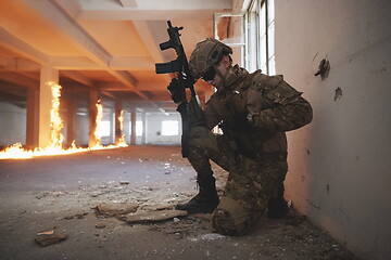 Image showing soldier in action near window changing magazine and take cover