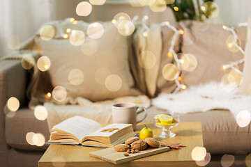 Image showing oat cookies, book, tea and lemon on table at home