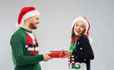 Image showing happy couple in christmas sweaters with gift box