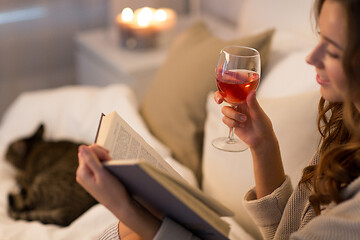 Image showing happy young woman reading book in bed at home