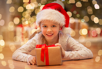 Image showing smiling girl in santa hat with christmas gift