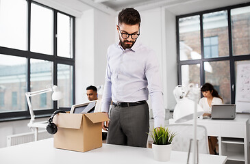 Image showing sad fired male office worker with personal stuff