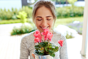 Image showing young woman with cyclamen flowers at summer garden