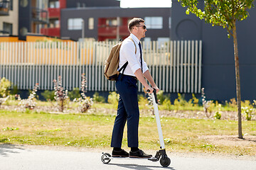 Image showing businessman with backpack riding electric scooter