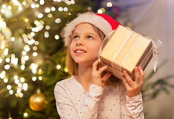 Image showing smiling girl in santa hat with christmas gift
