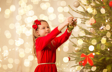 Image showing happy girl in red dress decorating christmas tree