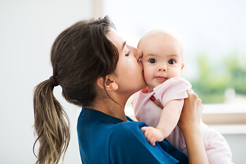 Image showing mother holding and kissing baby daughter at home