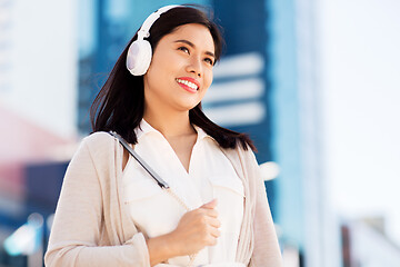 Image showing happy smiling asian woman with headphones in city