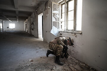 Image showing soldier in action near window changing magazine and take cover