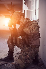 Image showing soldier in action near window changing magazine and take cover