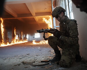 Image showing soldier in action near window changing magazine and take cover