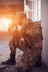 Image showing soldier in action near window changing magazine and take cover