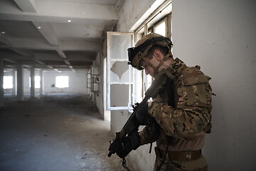 Image showing soldier in action near window changing magazine and take cover