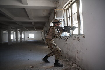 Image showing soldier in action near window changing magazine and take cover