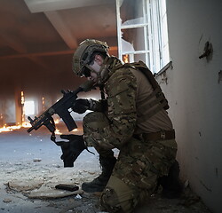 Image showing soldier in action near window changing magazine and take cover