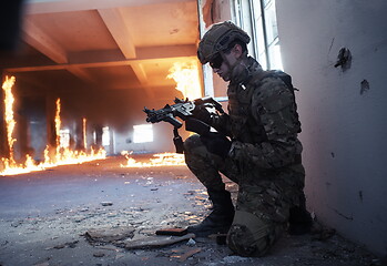 Image showing soldier in action near window changing magazine and take cover