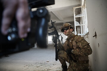 Image showing soldier in action near window changing magazine and take cover