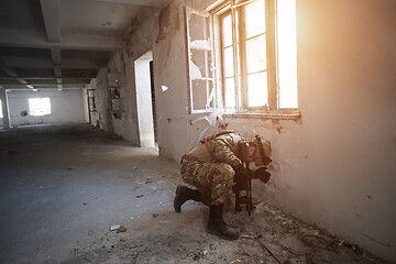 Image showing soldier in action near window changing magazine and take cover