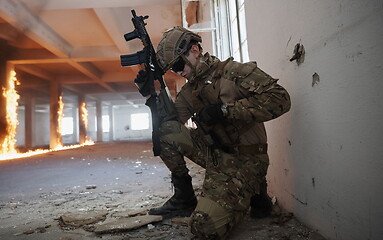 Image showing soldier in action near window changing magazine and take cover