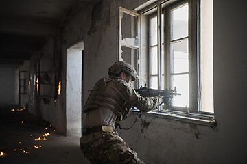 Image showing soldier in action near window changing magazine and take cover