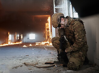 Image showing soldier in action near window changing magazine and take cover