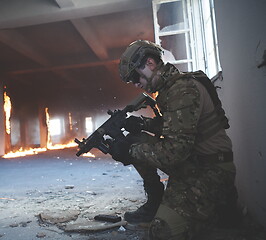 Image showing soldier in action near window changing magazine and take cover