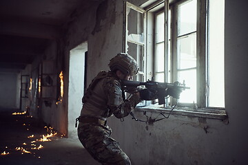 Image showing soldier in action near window changing magazine and take cover