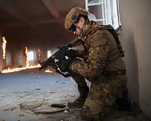 Image showing soldier in action near window changing magazine and take cover