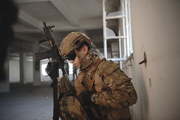 Image showing soldier in action near window changing magazine and take cover