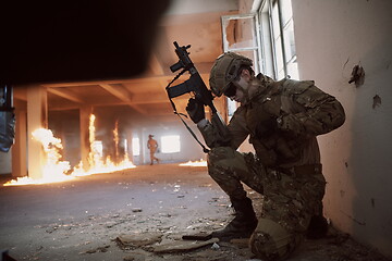 Image showing soldier in action near window changing magazine and take cover