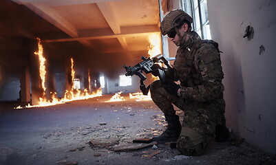 Image showing soldier in action near window changing magazine and take cover