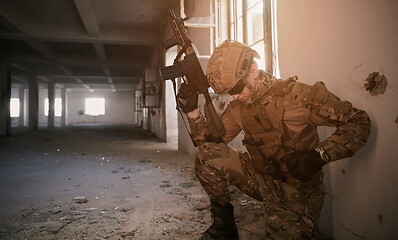 Image showing soldier in action near window changing magazine and take cover